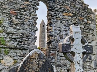 Der Friedhof von Glendalough mit Blick durch eine Steinmauer auf den Rundturm