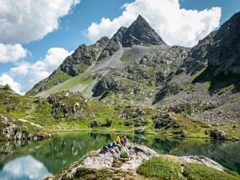 Deux coureurs de trail font une pause au bord d'un lac de montagne sur la Via Grischuna.