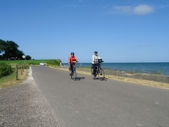 Zwei Radfahrer fahren auf einer Küstenstrasse