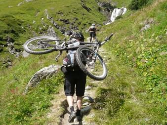 Strong person carrying the bike on their shoulders. Alpine bike. Cycling vacation with Eurotrek.