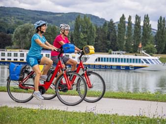 Zwei Radlerinnen am Ufer mit Schiff im Hintergrund