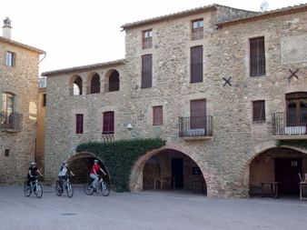 Velotour durch ein historisches Dorf in Nordkatalonien Radfahrer auf einem Platz mit traditionellen Steingebäuden