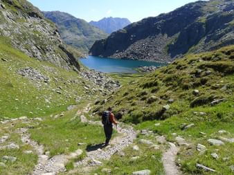 Ein Wanderer auf den Wanderwegen in Richtung Bergsee mit wunderschöner Berglandschaft.