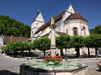 Une fontaine à St. Ursanne avec une église en arrière-plan