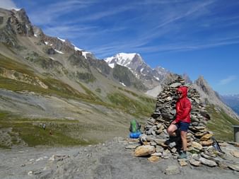Eine Wanderin lehnt sich an einen Berg aus Steinplatten an.