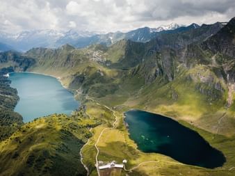 Luftaufnahme des Lago Ritom in den Alpen Vogelperspektive des Lago Ritom, ein dunkelblauer Alpensee umgeben von grünen Bergen und felsigen Gipfeln in den Schweizer Alpen.