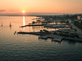 Die Sonne geht über dem Lac Léman unter und man sieht den Hafen von Lausanne.