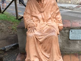 Eine sitzende Steinfiguer in der Farbe Terracotta der Nonna Lucia.