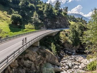 Two racing cyclists cross a bridge