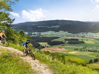 Cyclistes et, en arrière-plan, différents champs. Le vélo du Jura. Vacances à vélo avec Eurotrek.