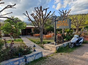 Schild eines Hotel am Strassenrand mit Garten und Gebäude im Hintergrund