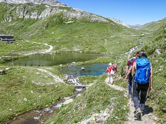 Un groupe de randonneurs se dirige vers un lac de montagne dans le Val d'Uina, dans le canton des Grisons.