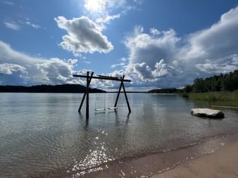 Eine Schaukel mit zwei Schaukeln aus Holz befindet sich im Wasser vom Meer.