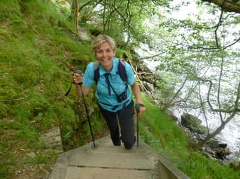 Eine Wanderin mit Stöcken wandert eine steile Treppe hinauf auf dem West-Highland-Way in Schottland.