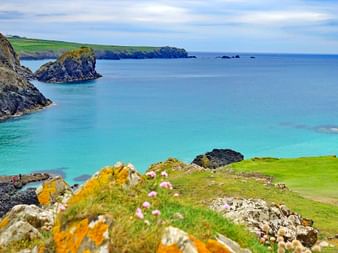 Vue à couper le souffle sur les eaux côtières turquoise de Cornouailles avec des falaises rocheuses spectaculaires et des prairies vertes.