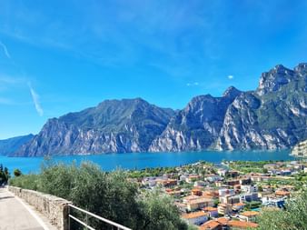 Vue panoramique du lac de Garde avec des montagnes spectaculaires s'élevant des eaux bleues. Une ville lakeside aux bâtiments colorés.