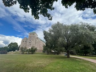 Typische Steinkirche in Finnland umgeben von Wiese und Laubbäumen.