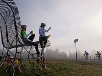 two cyclists sitting on a giant bench