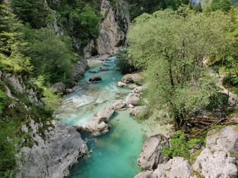 Türkisfarbener Fluss von oben fotografiert. Umgeben von Felsen und Bäumen.