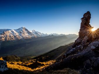 Coucher de soleil unique dans les Alpes bernoises. Les rayons du soleil brillent légèrement à droite derrière un sommet de montagne.