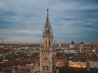Ausblick auf den Kirchturm von München mit der Stadt im Hintergrund.
