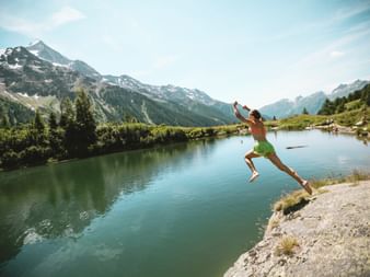 Eine Frau springt von einer Klippe in den Schwarzsee.
