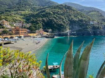 Malerische Bucht von Monterosso al Mare mit türkisfarbenem Wasser, Strand, bunten Gebäuden und grünen Terrassen in Cinque Terre, Ligurien.