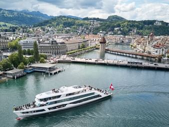 Ein weisses Schiff Namens MS Diamant fährt auf dem Luzernersee. Hinter ihm die Stadt Luzern.