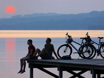 Cyclistes profitant du coucher de soleil sur une passerelle. Itinéraire sur l'Aar. Vacances à vélo avec Eurotrek.