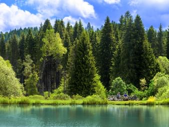 Deux cyclistes assis près d'un lac avec une forêt en arrière-plan