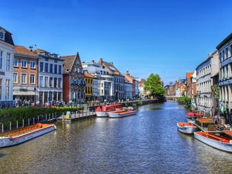 Historischer Kanal mit Booten in Gent Kanal in Gent gesäumt von bunten historischen Gebäuden und Ausflugsbooten. Mittelalterliche Architektur mit Treppengiebeln spiegelt sich im Wasser.