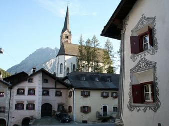 Die Häuser des Dorfes vor einer Kirche und einem Berg im Hintergrund.