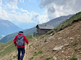 Ein Wanderer nähert sich einer Berghütte auf einem Bergpfad