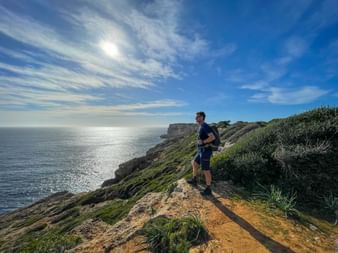Wanderer an den Felsen von Ses Falconeres mit Panoramablick auf das Meer