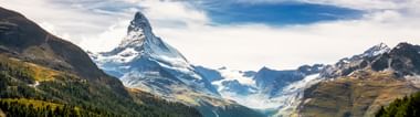 Das Schneebedekte Matterhorn vor einer grünen Alenwiesen-Landschaft.