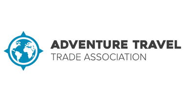 Logo mit blauer Kompassrose mit Globussymbol und Text 'Adventure Travel Trade Association' in dunkelgrauer und hellgrauer Schrift.