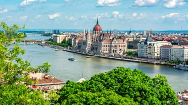 Panoramablick auf das ungarische Parlamentsgebäude mit seiner markanten roten Kuppel und neugotischen Architektur an der Donau in Budapest.