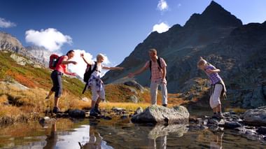 Famille traversant un cours d'eau. L'Albula et la Bernina. Vacances à pied avec Eurotrek.