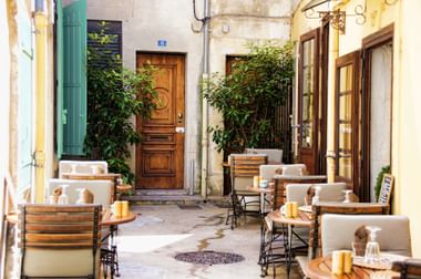Ein kleines, traditionelles Café liegt in einem Hinterhof umgeben von alten Gebäuden in Frankreich.