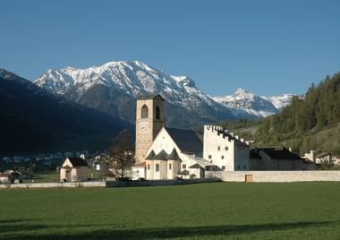Le monastère Saint-Jean de Müstair avec des montagnes en arrière-plan.