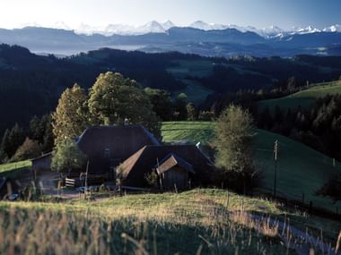 Ein kleiner Bauernhof sitzt inmitten ruhiger Natur mit Aussicht auf die Alpen im Emmental im Kanton Bern.