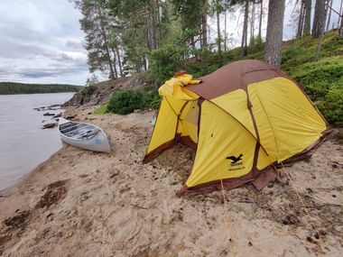 Das aufgestellte gelbe Zelt an einem Sandstrand.