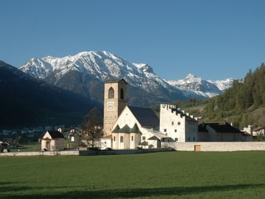 Le monastère Saint-Jean de Müstair avec des montagnes en arrière-plan.