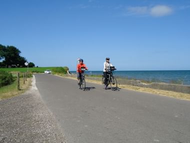 Zwei Radfahrer fahren auf einer Küstenstrasse