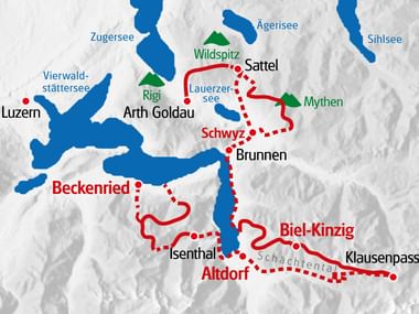Map showing hiking routes in red through Swiss towns Beckenried, Schwyz, and Biel-Kinzig, with blue lakes including Zugersee and Vierwaldstättersee.