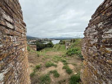 Blick zwischen steinernen Festungsmauern in Valença auf den Minho-Fluss und die Landschaft unter bewölktem Himmel.
