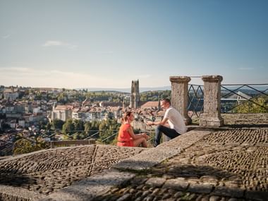 A couple sitting on a stone staircase with a view of a city.