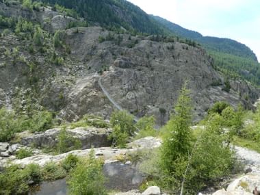 kaum sichtbar, über der Schlucht eine Hängebrücke.