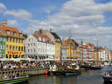 Uferpromenade in Kopenhagen mit Booten, vielen Menschen und typisch traditionelle Häuser in Dänemark.