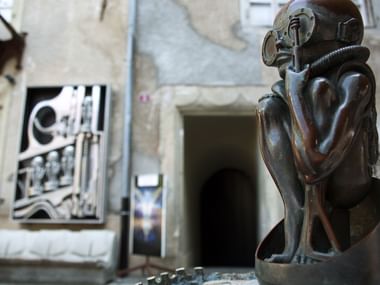 Eine Metallstatue steht an einem Eingang des Gigermuseums Gruyères.